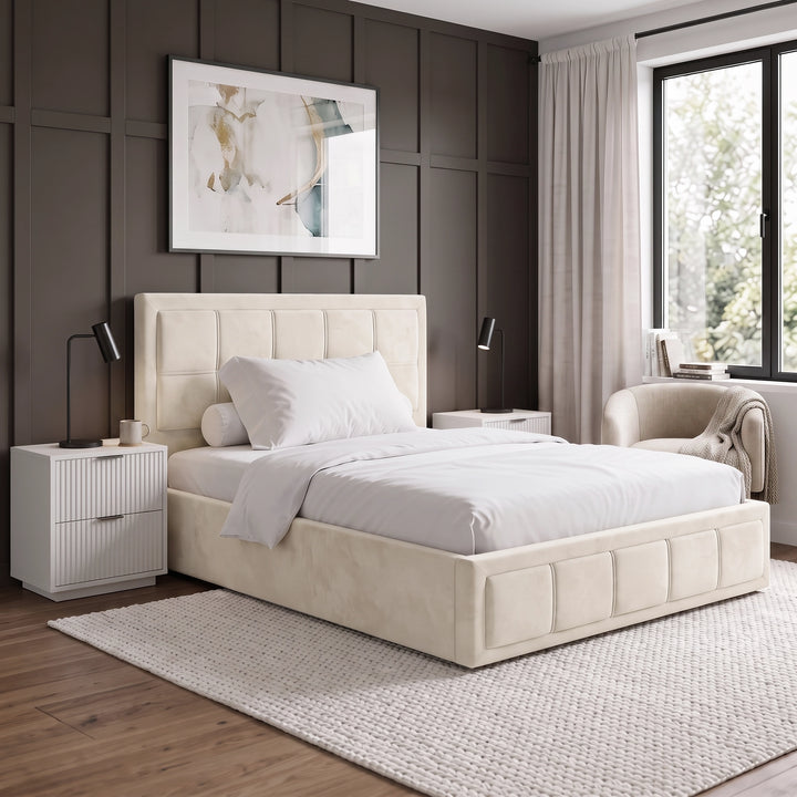 [Small Double | Beige] Side perspective view of the Small Double Beige Velvet Ottoman Storage Bed Frame flanked by white bedside tables.
