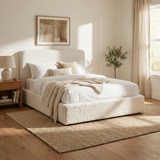 [White | King] King Sofna boucle ottoman bed three-quarter, rounded headboard beside oak nightstand in sunlit room