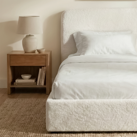 [White | Single] Side view of single boucle ottoman bed showing textured fabric base beside wooden nightstand with lamp
