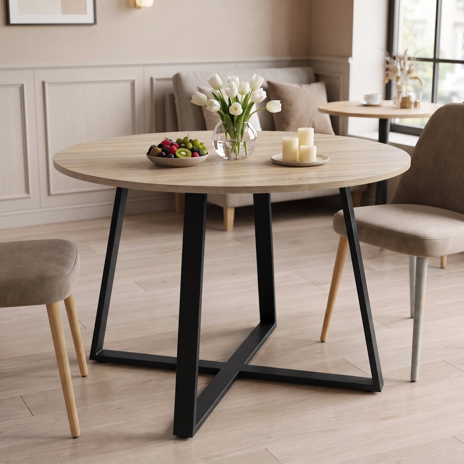 [Sonoma Oak] Round light oak-effect dining table in a bright room with flowers, fruit and candles on the tabletop.