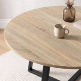 [Sonoma Oak] Close-up of the round light oak-effect tabletop with natural-looking grain, styled with a cup, vase and paper.