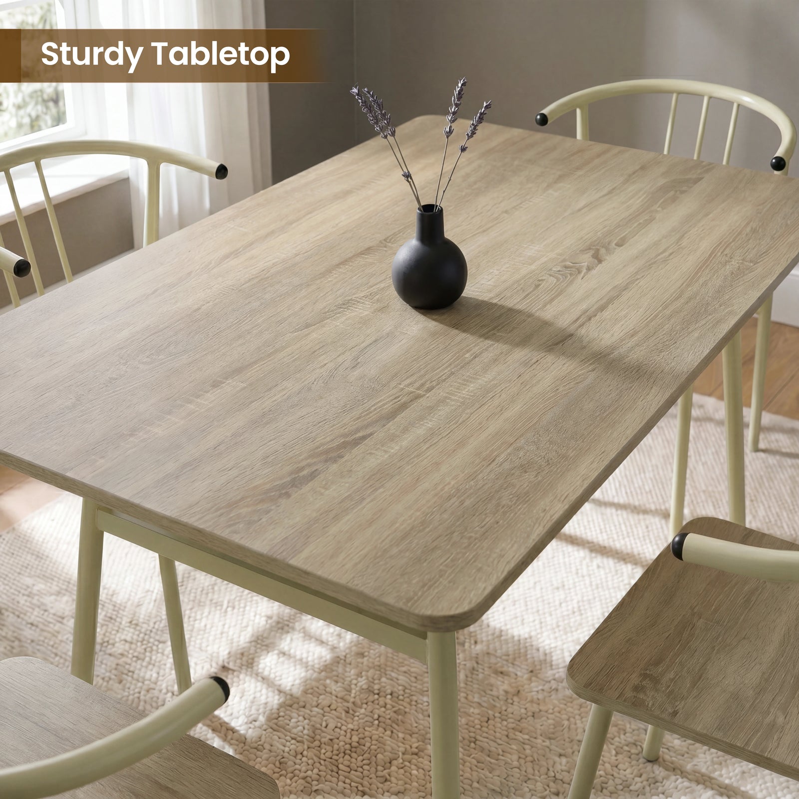 [Sonoma Oak] Torvi dining table and chairs overhead close-up showing oak-effect tabletop surface with a small vase and four cream metal arm chairs around it