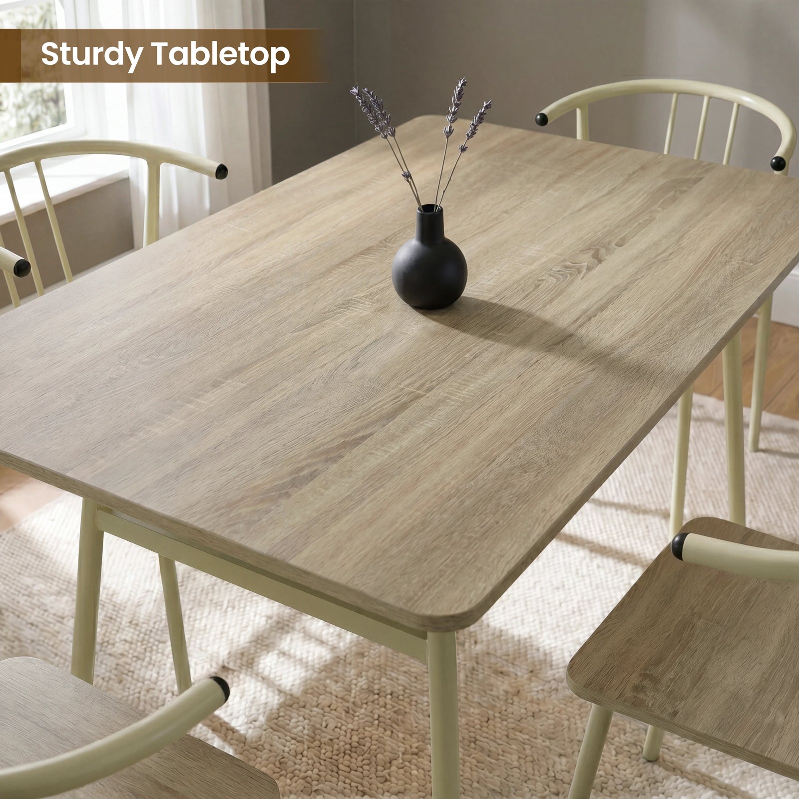 [Sonoma Oak] Torvi dining table and chairs overhead close-up showing oak-effect tabletop surface with a small vase and four cream metal arm chairs around it