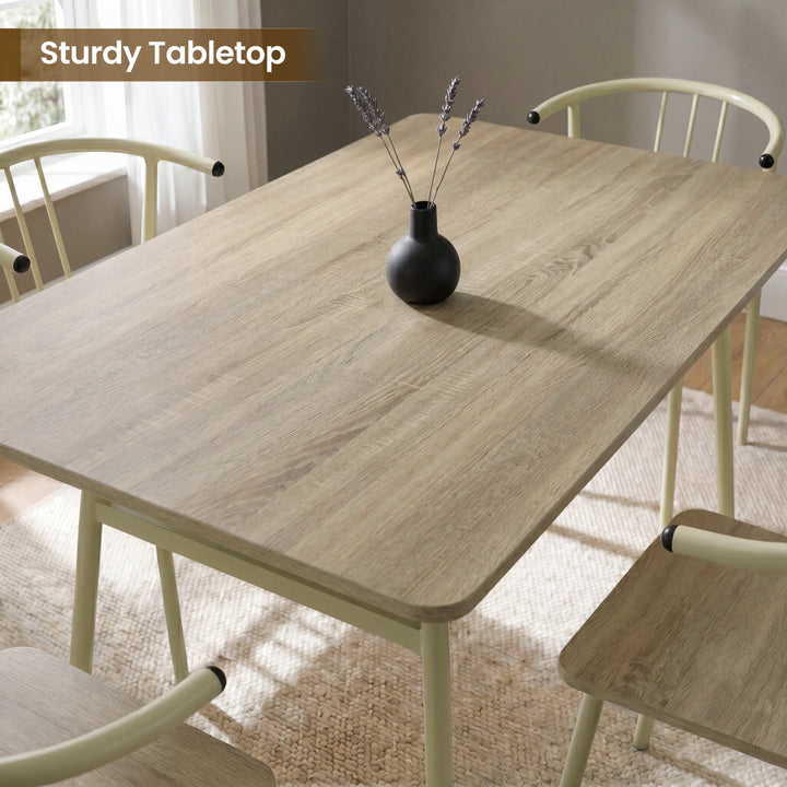 [Sonoma Oak] Torvi dining table and chairs overhead close-up showing oak-effect tabletop surface with a small vase and four cream metal arm chairs around it