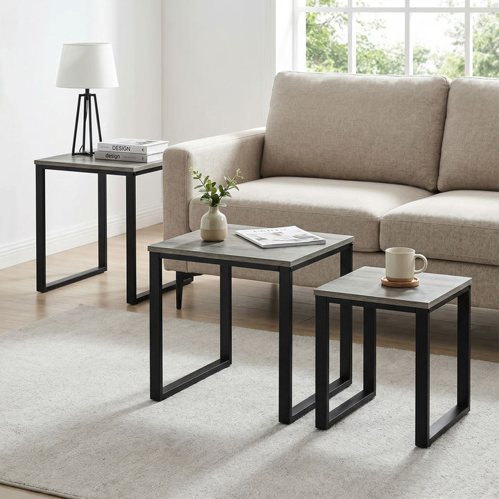 [Grey Wooden] Stackora set of 3 nesting tables angled lifestyle view in a living room with accessories on grey tops