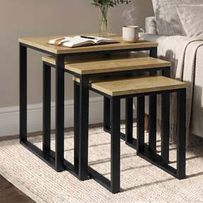 [Oak] Stackora set of 3 nesting tables angled view in a living room with sofa and accessories on oak tops