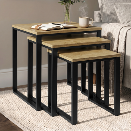 [Oak] Stackora set of 3 nesting tables angled view in a living room with sofa and accessories on oak tops