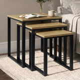 [Oak] Stackora set of 3 nesting tables angled view in a living room with sofa and accessories on oak tops