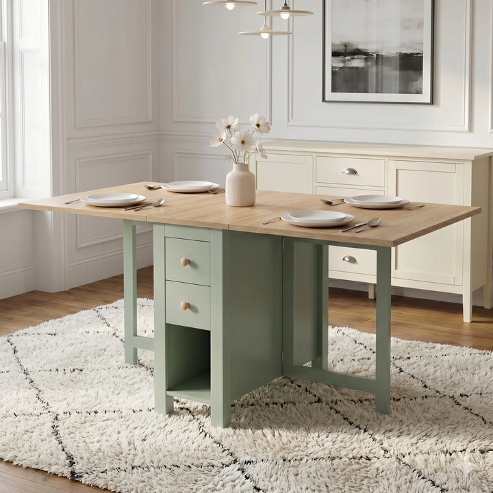 [Green] Stovra Drop Leaf Dining Table with Storage 150cm fully extended into a four-person setup with white plates, a central flower vase, and drawers 