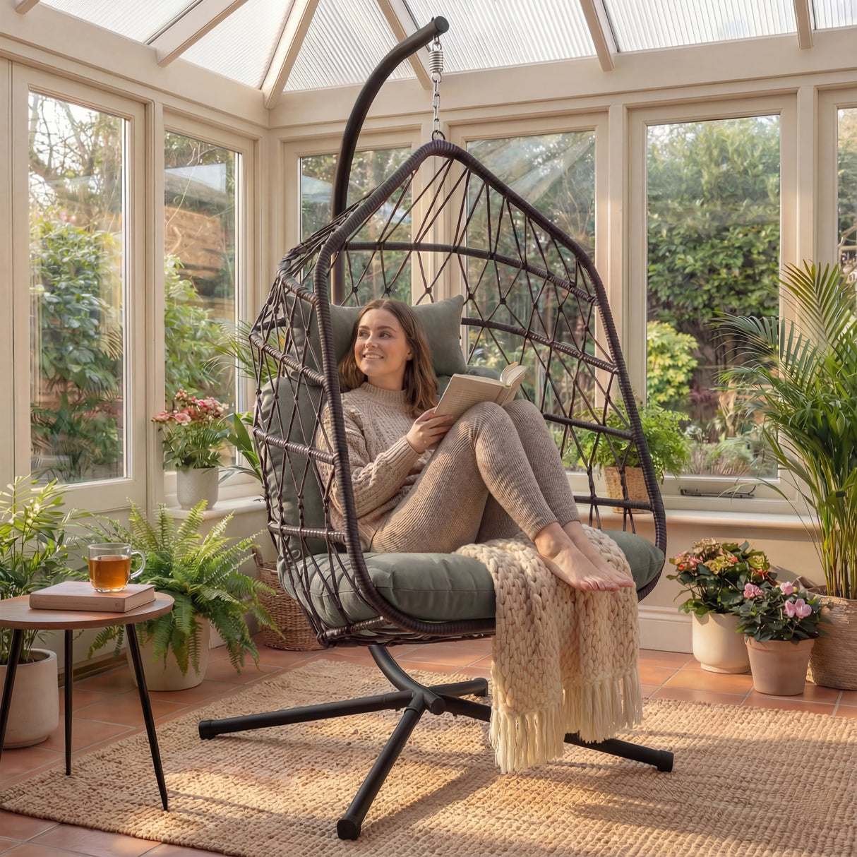 A girls seating in grey swinging egg chair with a sturdy stand, placed in sunlit room, offering ultimate relaxation