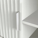 Sleek white TV media unit with vertical ribbing and silver handle, styled with books and minimalist home decor.