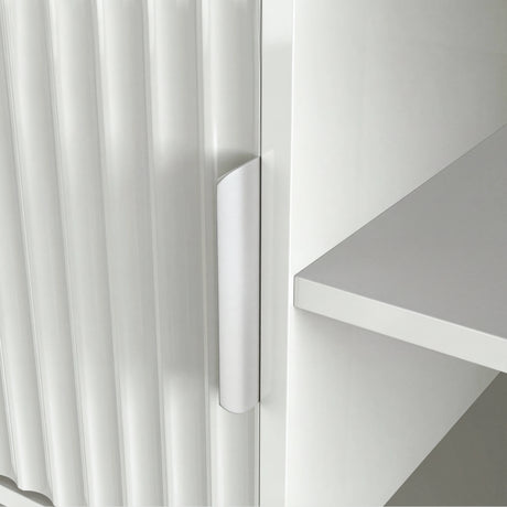 Sleek white TV media unit with vertical ribbing and silver handle, styled with books and minimalist home decor.