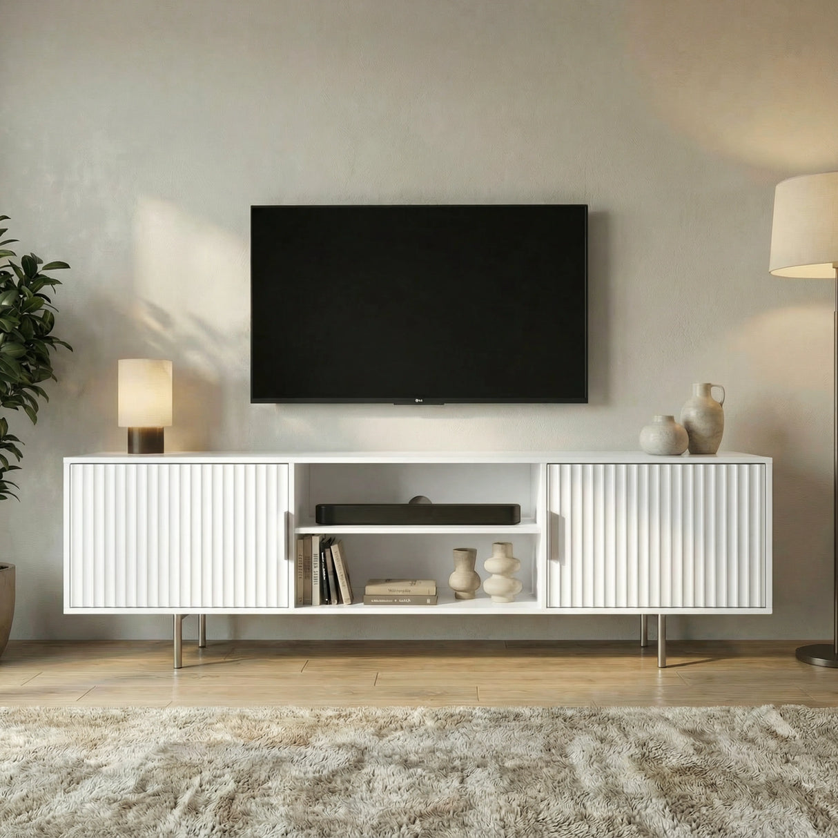 Modern white TV stand with vertical fluted doors, open shelving, and silver legs for a minimalist living room.