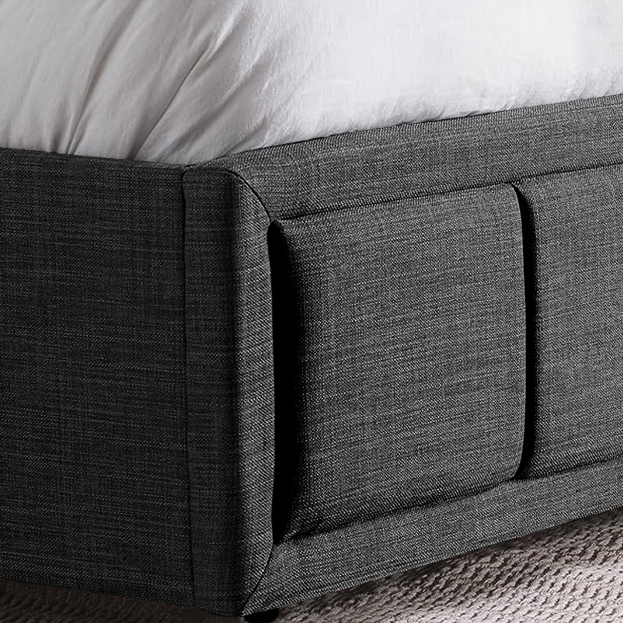 Close-up of dark grey ottoman bed frame corner with fabric upholstery and under-bed storage detail.