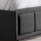 Close-up of dark grey ottoman bed frame corner with fabric upholstery and under-bed storage detail.