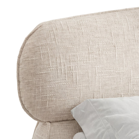 Close detail of a beige upholstered headrest with softly curved edges of king-size bed frame