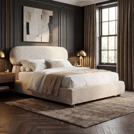 Beige upholstered double bed frame shown in a softly lit bedroom with layered bedding and accent cushions