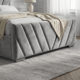 Side view of the V-shaped design on the footboard of a grey velvet ottoman bed, showcasing fabric texture