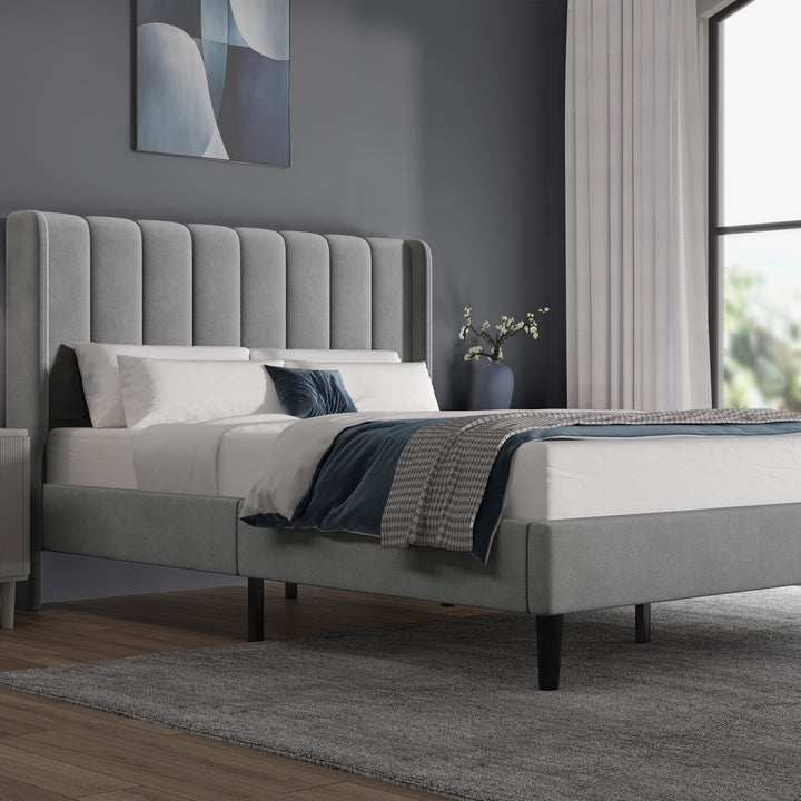 [King | Light Grey] Side angle of velvet bed with vertical channel-tufted headboard and low footboard on dark legs