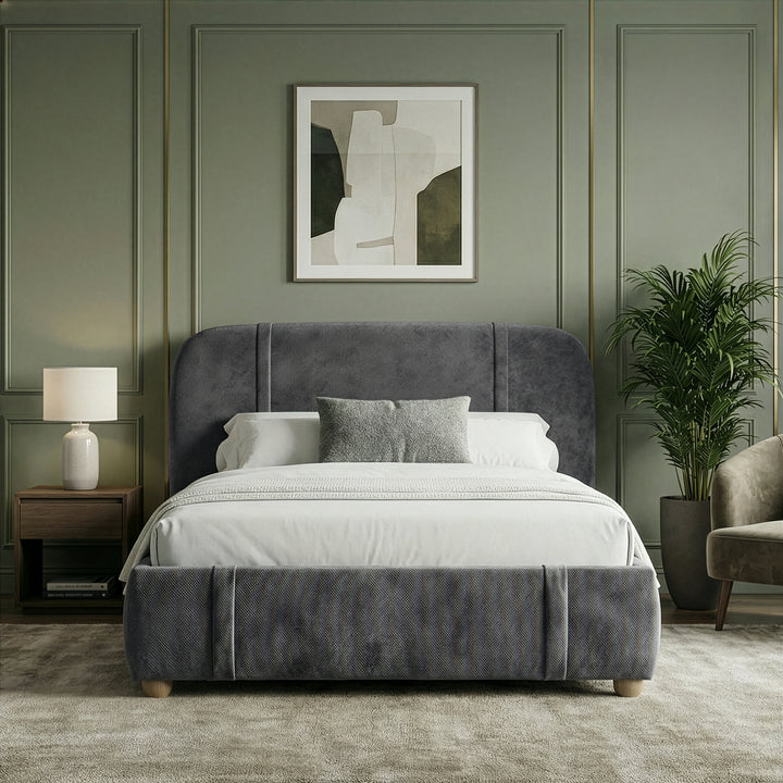 [Double | Dark Grey] Front view of fabric bed with wingback headboard between white nightstand and beige armchair
