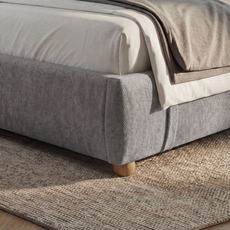 [Double | Grey] Close-up of bed frame corner showing rounded padded edge with wooden cylinder foot on jute rug