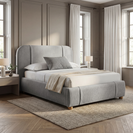 [King | Grey] Upholstered bed from the side with padded headboard and beige throw beside white nightstand