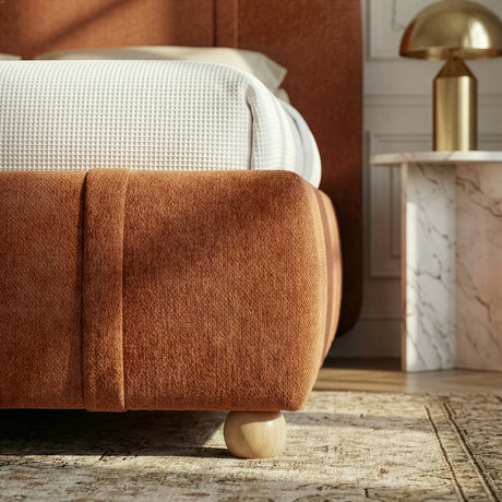 [King | Orange] Close-up of footboard corner showing rounded padded edge with wooden ball foot and vertical stitching