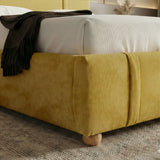[King | Yellow] Close-up of footboard corner showing rounded padded edge with wooden ball foot on grey rug