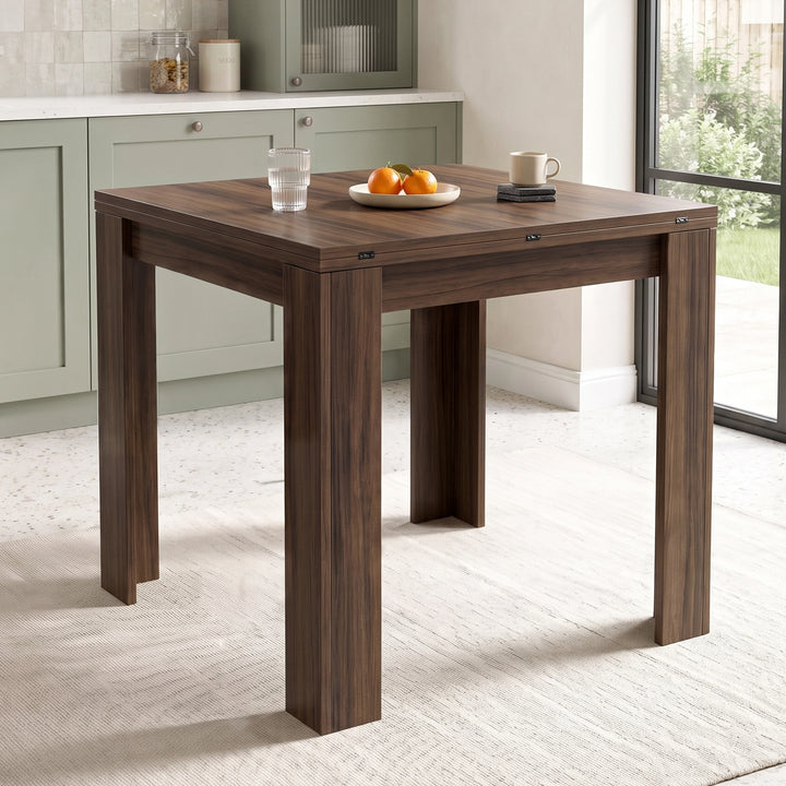 [Walnut] Close-up closed wood-grain square tabletop, steel hinges, wide legs, water glass, oranges and cream mug on coasters