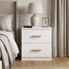 White two drawer bedside table placed beside bed with wooden handles and neutral bedroom decor