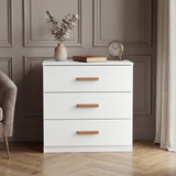 [White] Front view of white three drawer chest against neutral wall with smooth drawer fronts and flat top