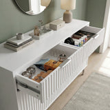 [White] chest of drawers with decorative items and open drawers against a green wall placed in a natural light room