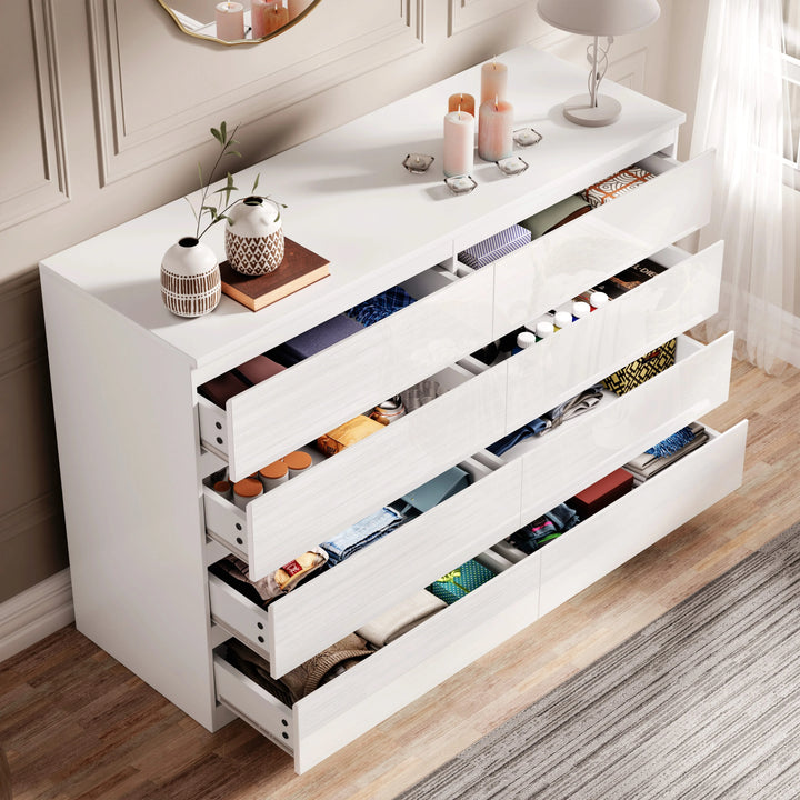 [White] high gloss wide chest of drawers fully open displaying folded textiles in every drawer