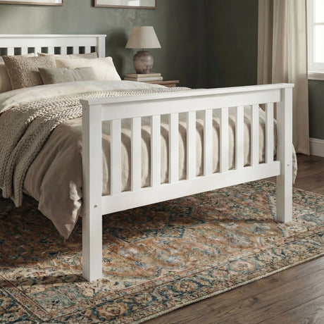 Slatted design white wooden bed frame with underbed storage space placed on a wooden flooring in a bedroom
