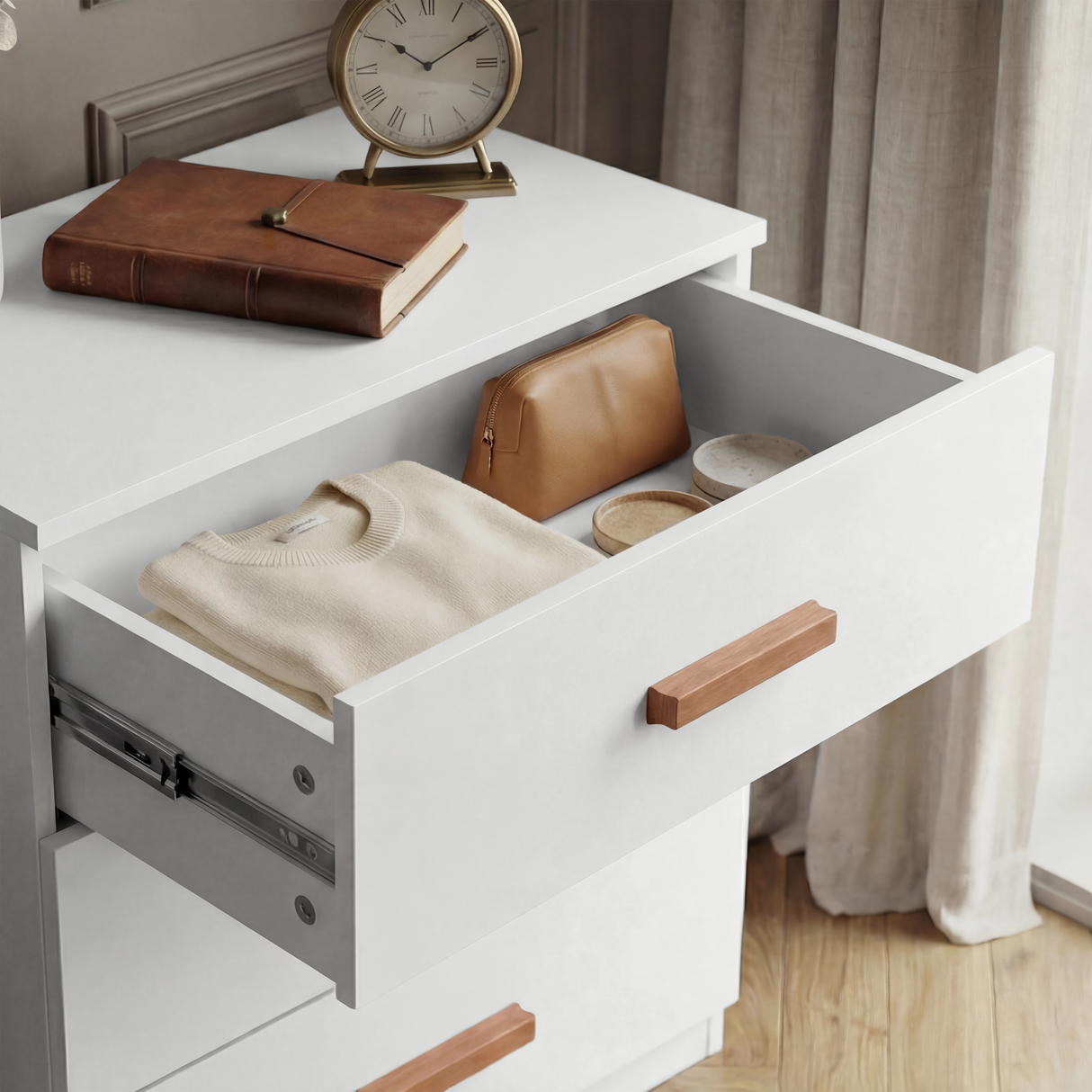 [White] Open top drawer of the white chest, revealing the interior storage space and the wooden handle detail