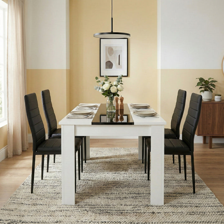 [4 Seater | Black] White & Black Gloss 4-6 Seater Dining Table with four black faux-leather chairs set for two in a bright yellow-toned dining room with pendant light