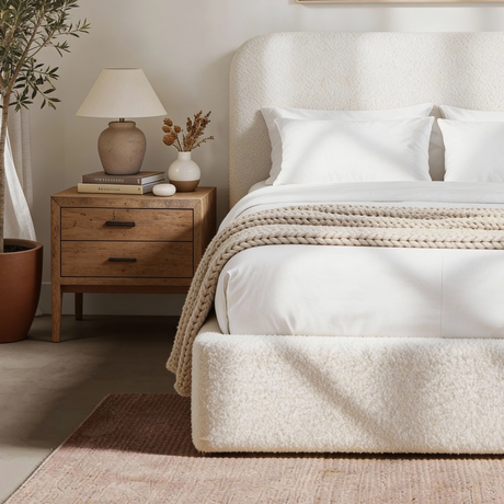 Side view of white boucle king bed displaying textured fabric base and low upholstered frame design
