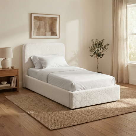 Angled room view of white boucle single ottoman storage bed highlighting textured fabric and padded headboard