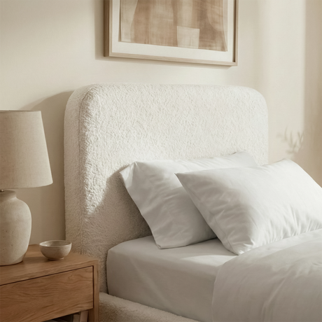 Close view of white boucle single bed headboard with soft textured upholstery and gently curved padded design