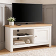 [White] TV stand with a light wood top, shown in a styled room setting with a flat-screen TV, a small potted plant, and decorative items on and inside the shelves