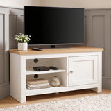 [White] TV stand with a light wood top, shown in a styled room setting with a flat-screen TV, a small potted plant, and decorative items on and inside the shelves