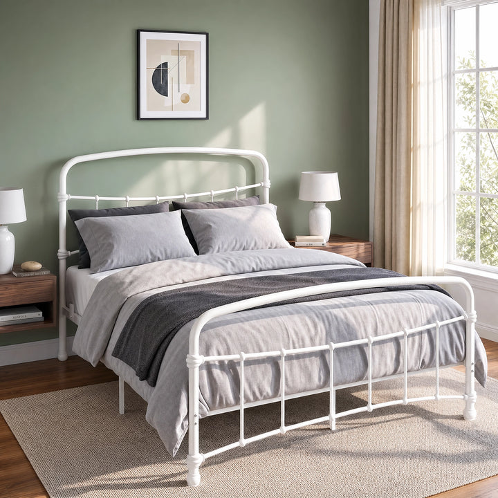 [White | Double] Close view of the white curved front rail, vertical bars and white bedding beside a small table.