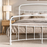 [White | King] Close view of the white curved front rail, vertical bars and taupe bedding beside a lamp.