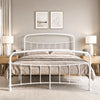 [White | King] Front view of a white metal bed frame with curved rails and taupe bedding in a bright bedroom.