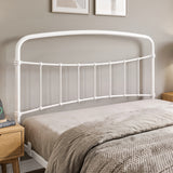 [White | King] Close-up of the white curved headboard with vertical bars, taupe pillows and layered bedding.