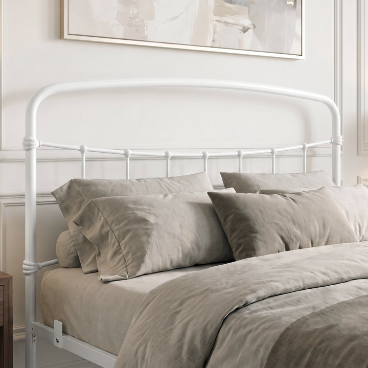 [White | King] Close-up of the white curved headboard with vertical bars, taupe pillows and layered bedding.