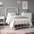 [White | Single] White metal bed frame with white bedding, shown at a 3/4 Angle in a bright bedroom with a rug.