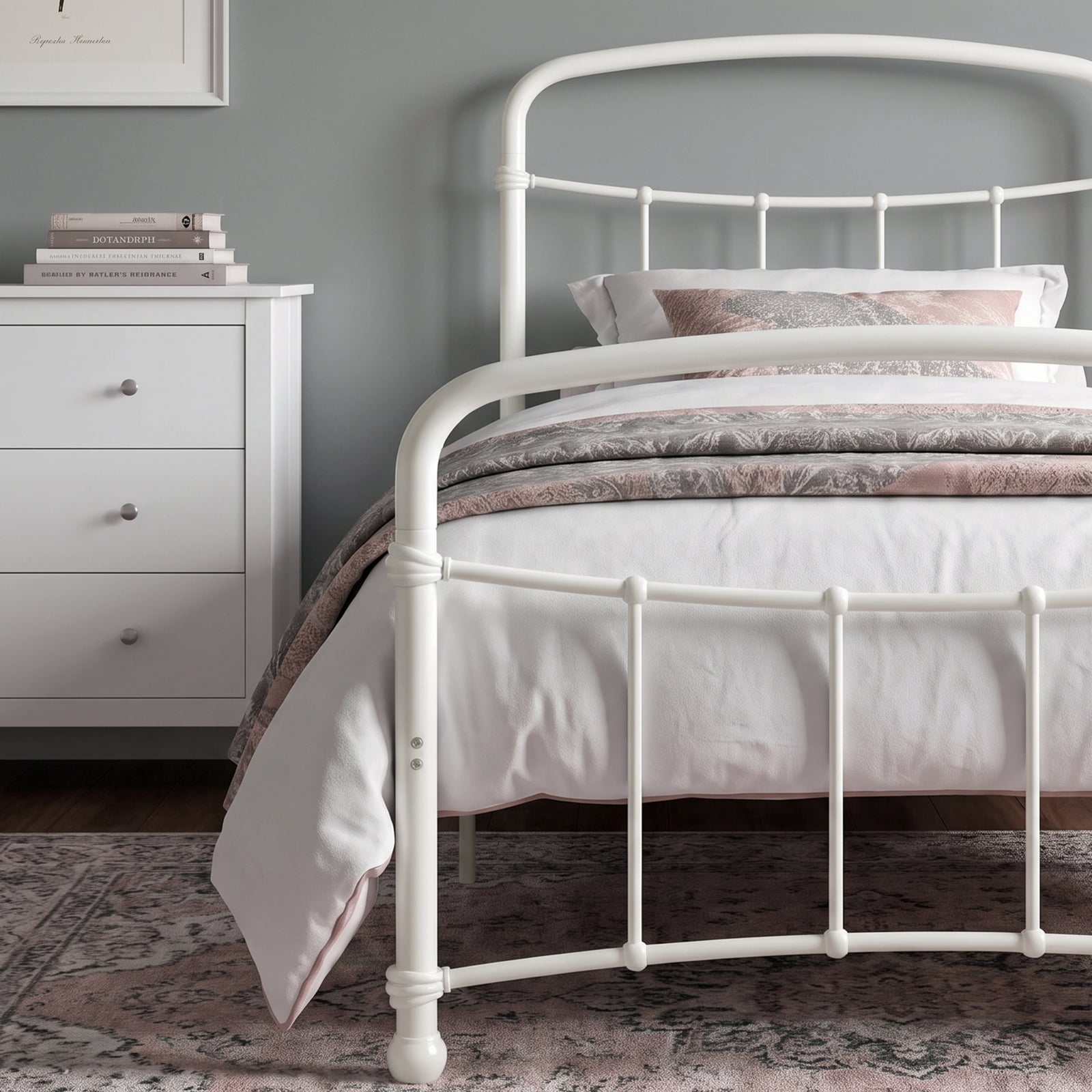 [White | Single] Close view of the white curved front rail, vertical bars and white bedding beside a small table.