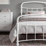 [White | Single] Close view of the white curved front rail, vertical bars and white bedding beside a drawers