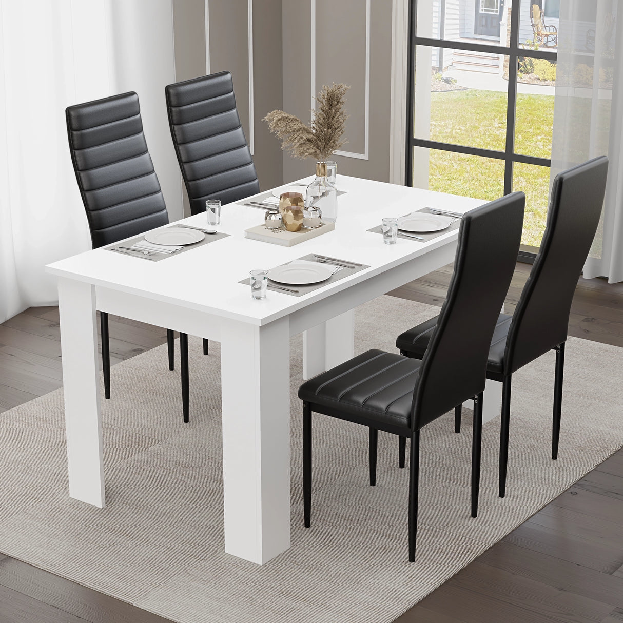 Modern white dining table set for four, paired with sleek black chairs. Styled in a contemporary dining room featuring elegant wall art and a statement chandelier — ideal for small families or compact spaces.